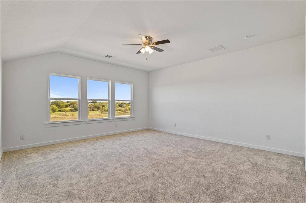 Vaulted ceiling with a contemporary ceiling fan, three large windows, neutral-toned carpeting, and light-colored walls