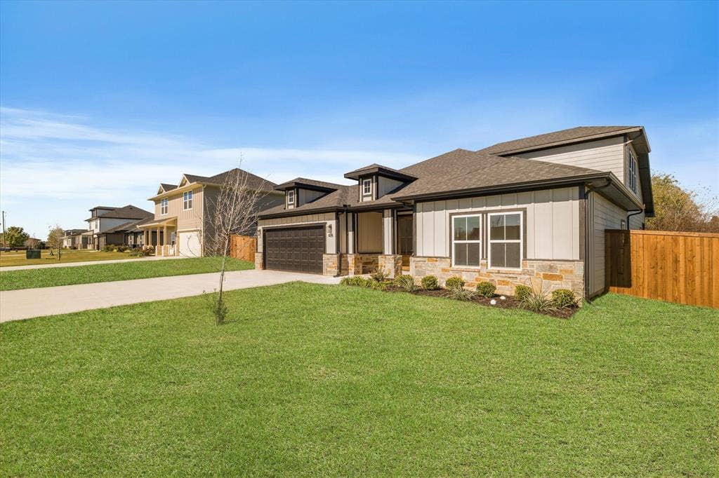 Exterior featuring stone and siding finishes, a two-car garage, fenced yard, and a concrete driveway