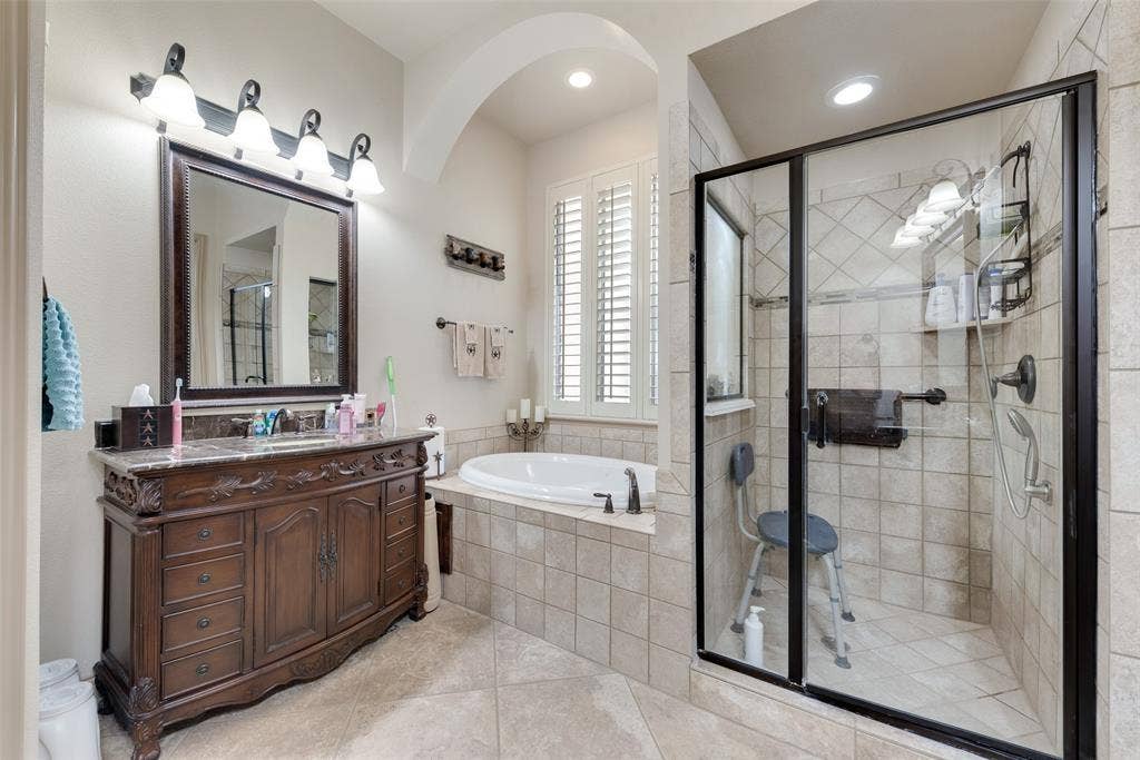 5056 Empire Way, Irving, TX 75038 Downstairs Primary Bathroom #1 with separate vanities, tile patterned flooring, and separate shower and bath