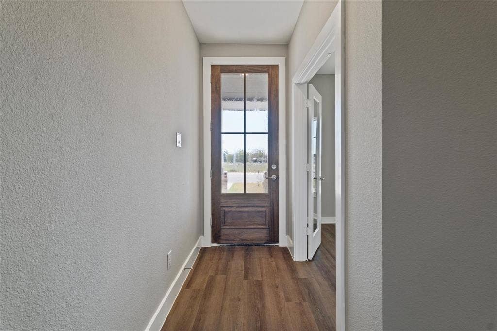 Wood-finish flooring, full-light front door with grid, white trim, and light gray wall paint