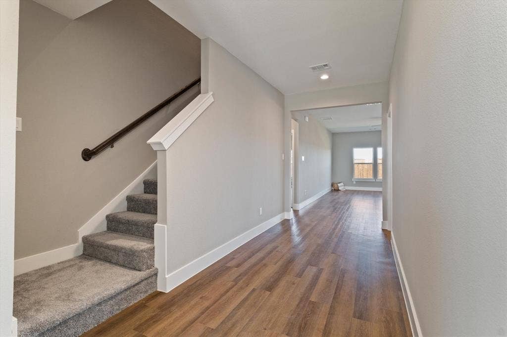 Staircase with carpeted treads and dark-finish handrail