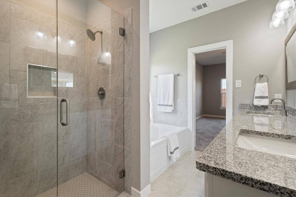 Glass-enclosed shower with a recessed shelf and hexagonal tile floor