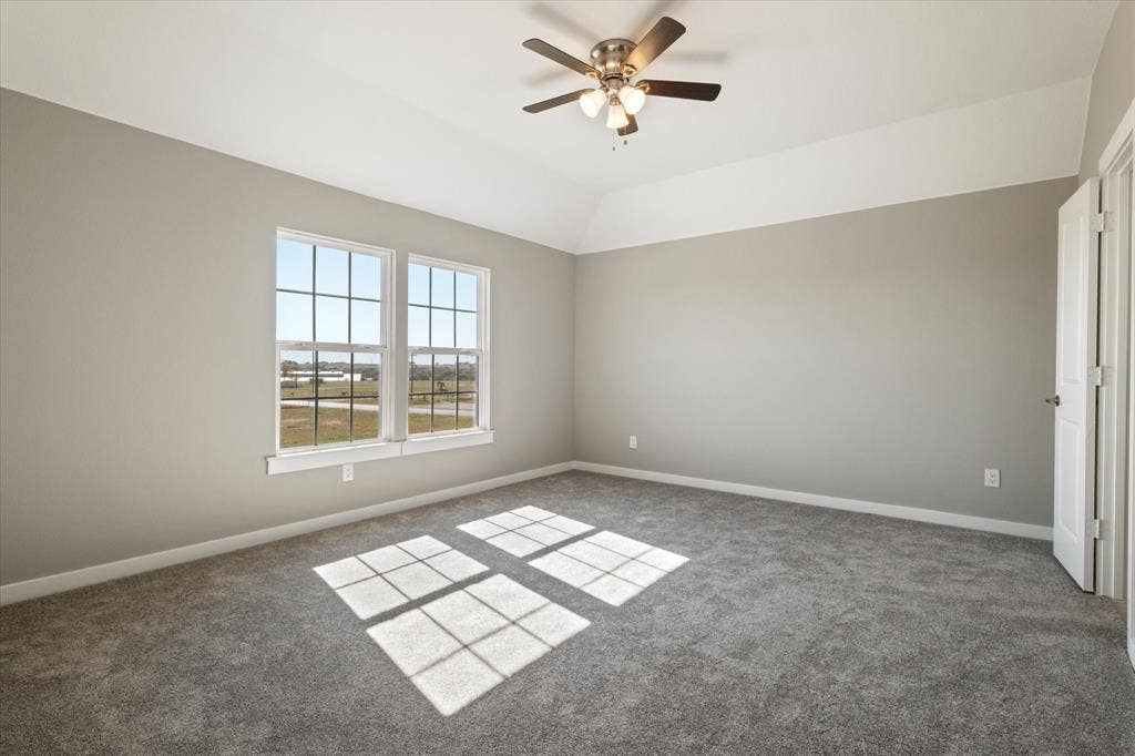 Two pane windows, neutral gray walls, gray carpeting, tray ceiling, and a ceiling fan