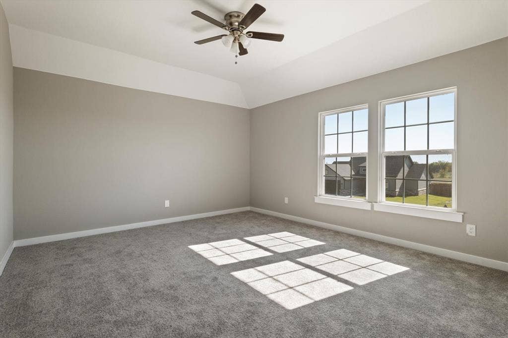 Tray ceiling, two gridded windows, ceiling fan with integrated lighting, wall-to-wall carpeting, and neutral paint finishes
