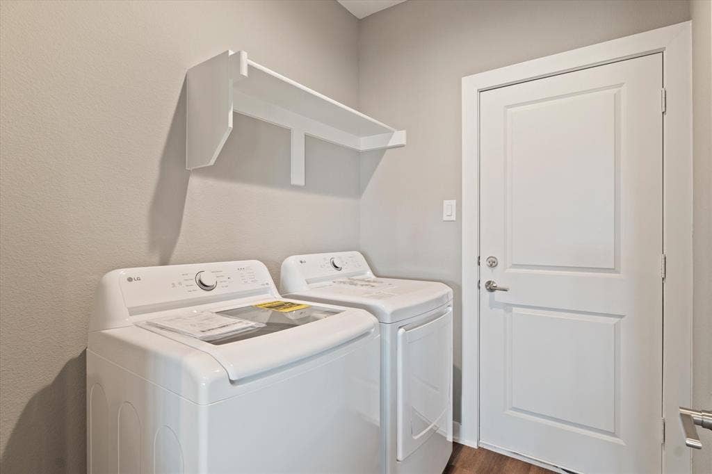 Laundry area featuring a wall-mounted shelf, light gray walls, and wood-finish flooring