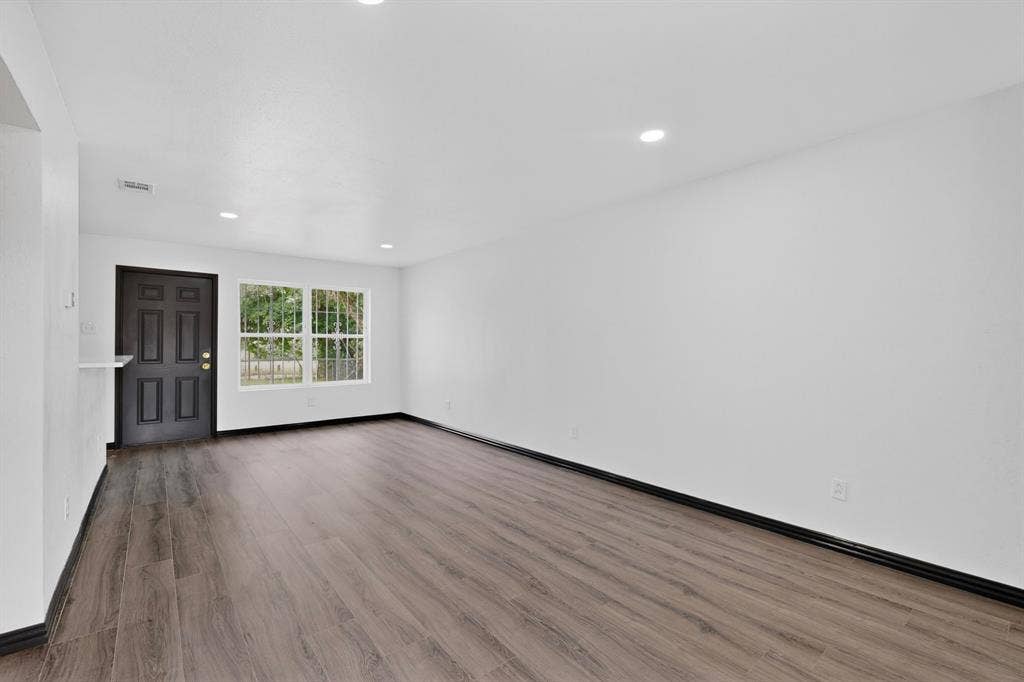 301 Stoneport Drive, Dallas, TX 75217 Recessed lighting illuminating wood-finish flooring, white walls, and dark trim