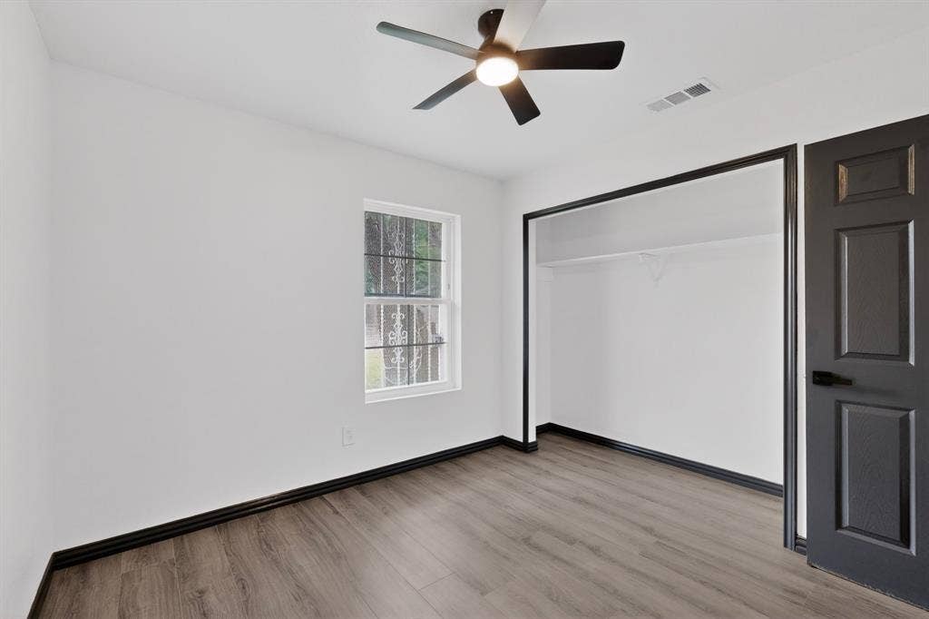 301 Stoneport Drive, Dallas, TX 75217 Recessed closet with built-in shelving, wood-finish flooring, white walls, and a ceiling fan with integrated lighting