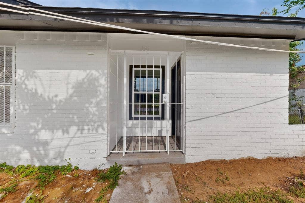 301 Stoneport Drive, Dallas, TX 75217 White painted brick exterior with dark trim and white security bars