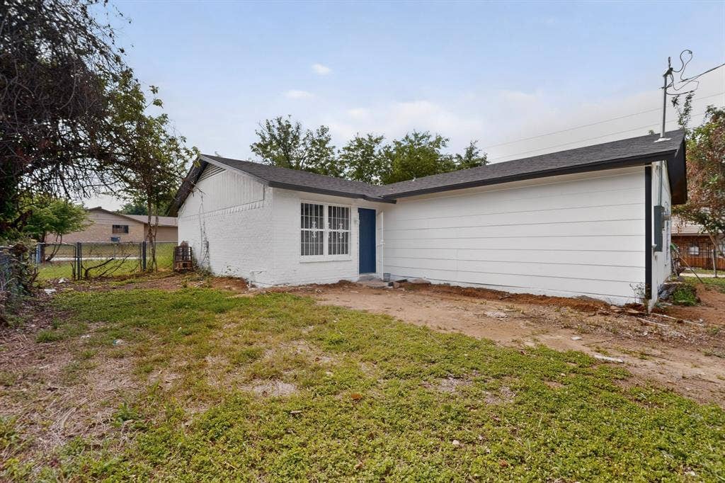 301 Stoneport Drive, Dallas, TX 75217 White exterior siding with a dark roof and a blue exterior door