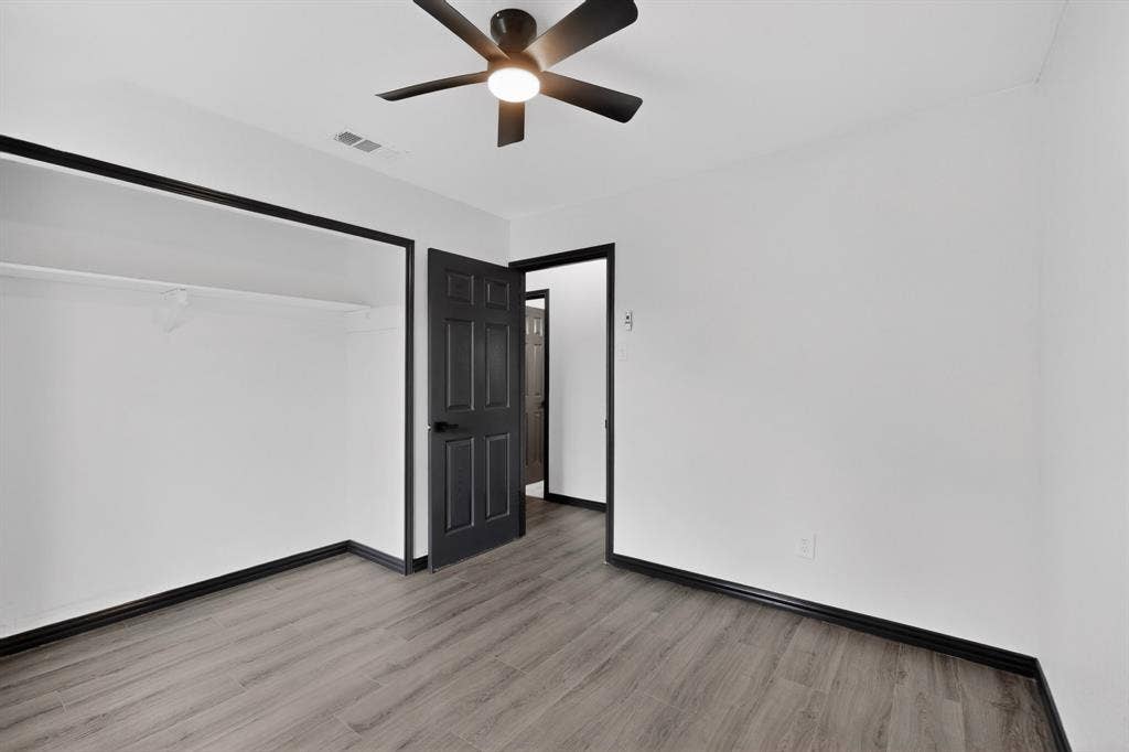 301 Stoneport Drive, Dallas, TX 75217 Wood-finish flooring with dark trim, ceiling fan with integrated lighting, and a built-in closet with shelving