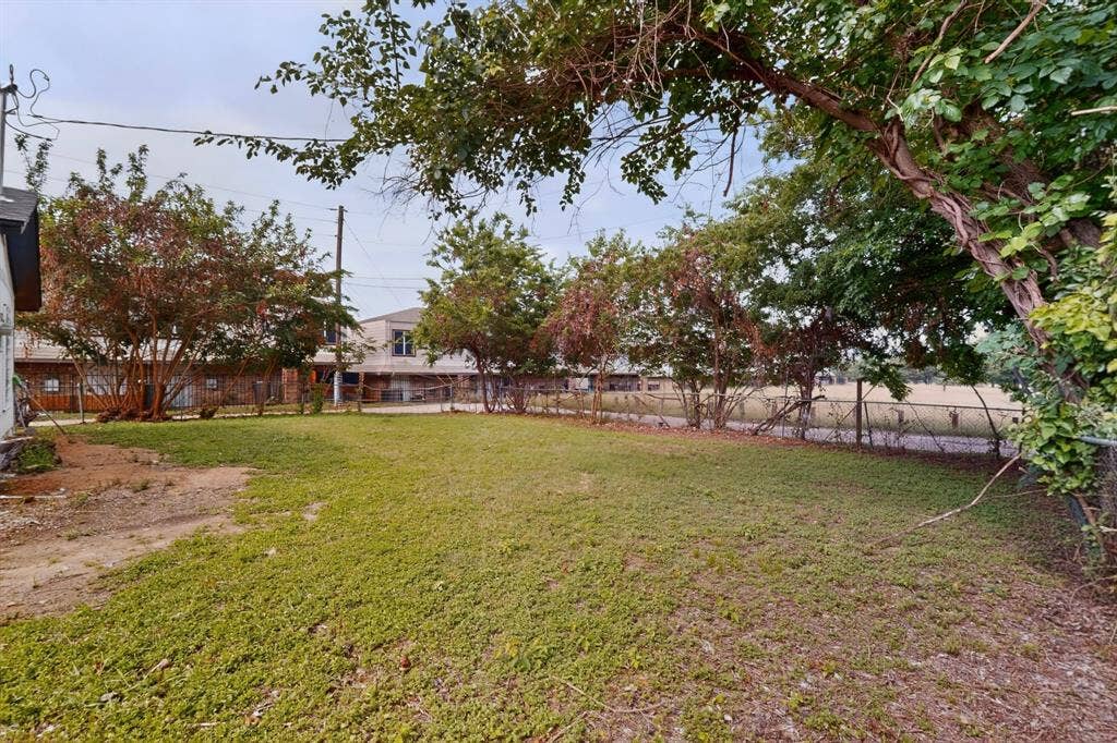 301 Stoneport Drive, Dallas, TX 75217 Expansive yard featuring natural ground cover and a chain-link fence