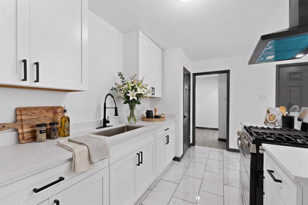 301 Stoneport Drive, Dallas, TX 75217 White shaker-style cabinetry with matte black hardware, light-toned countertops, tile flooring, and a stainless steel sink with a matte black faucet