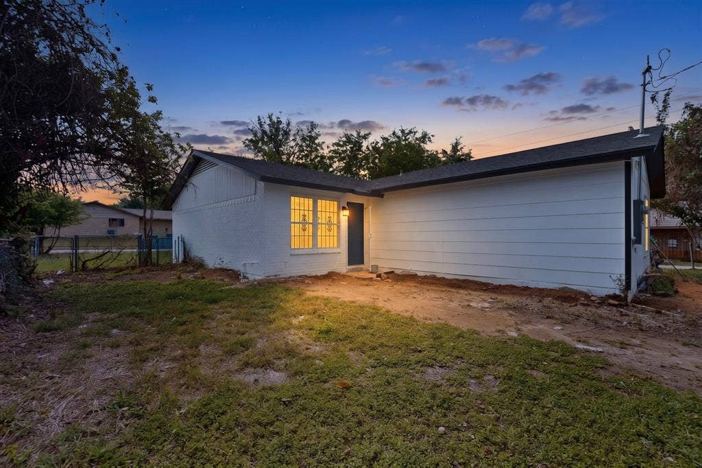 301 Stoneport Drive, Dallas, TX 75217 White exterior siding with a dark roof and a prominent window