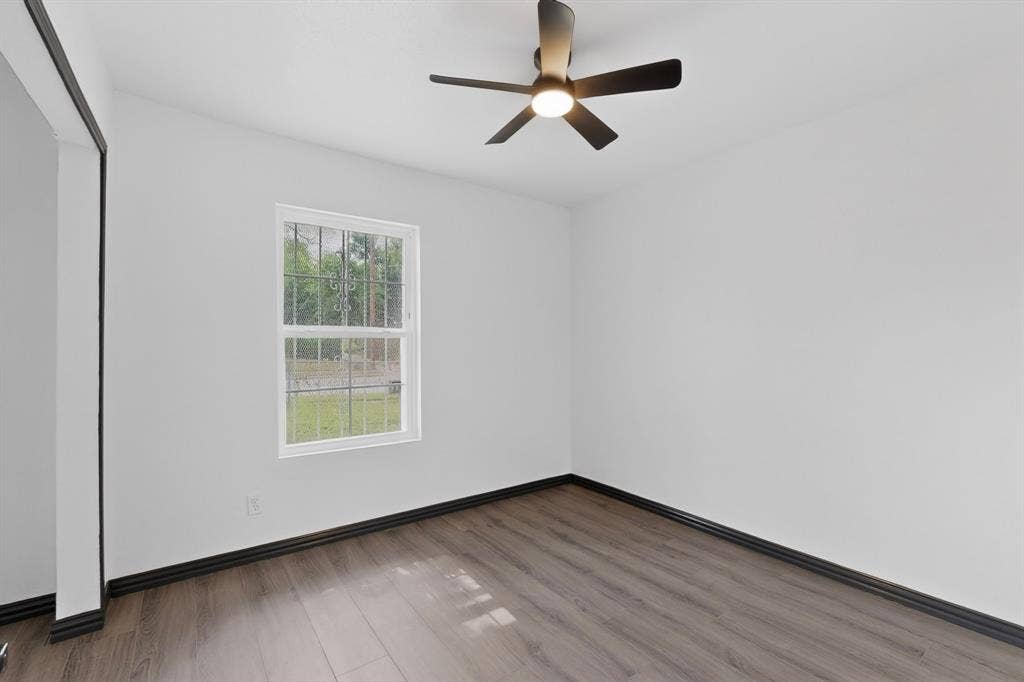 301 Stoneport Drive, Dallas, TX 75217 Wood-finish flooring with dark trim, white painted walls, and a ceiling fan with integrated lighting
