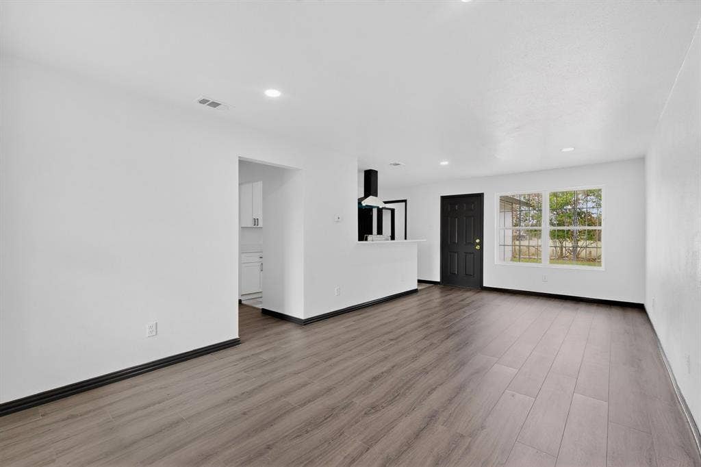301 Stoneport Drive, Dallas, TX 75217 Open concept living space featuring wood-finish flooring, recessed lighting, and a kitchen pass-through with a contemporary range hood