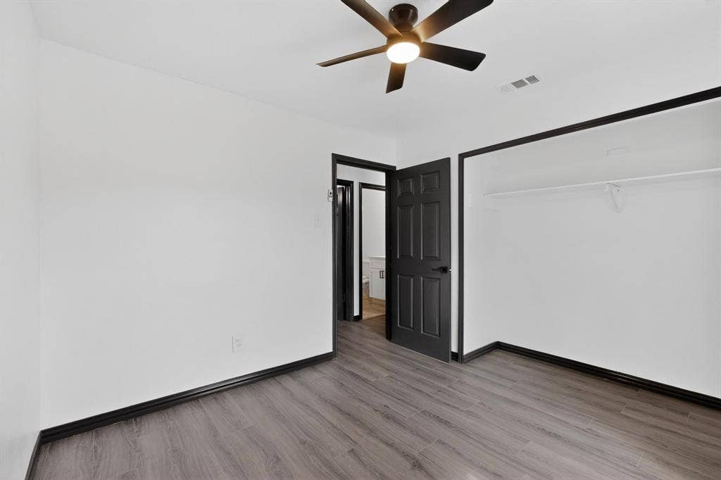301 Stoneport Drive, Dallas, TX 75217 Wood-finish flooring, ceiling fan with integrated lighting, built-in closet shelving, and dark trim details