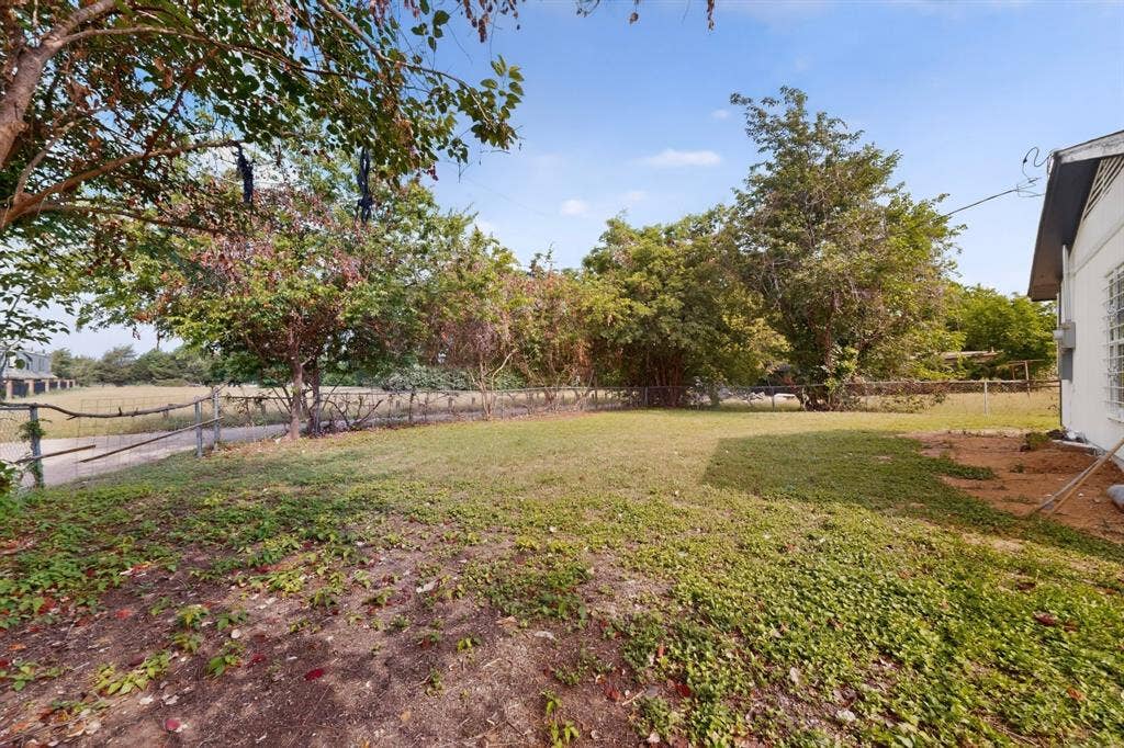 301 Stoneport Drive, Dallas, TX 75217 Expansive grassy yard with mature trees and a partial wood fence