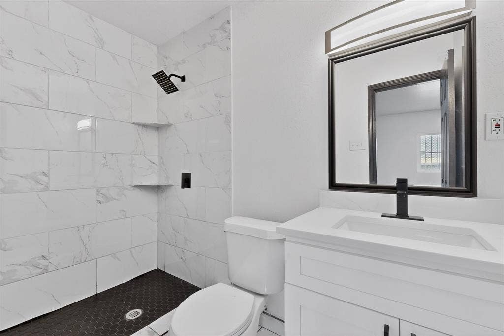 301 Stoneport Drive, Dallas, TX 75217 Shower featuring white marble-look subway tile and a black hexagonal tile floor