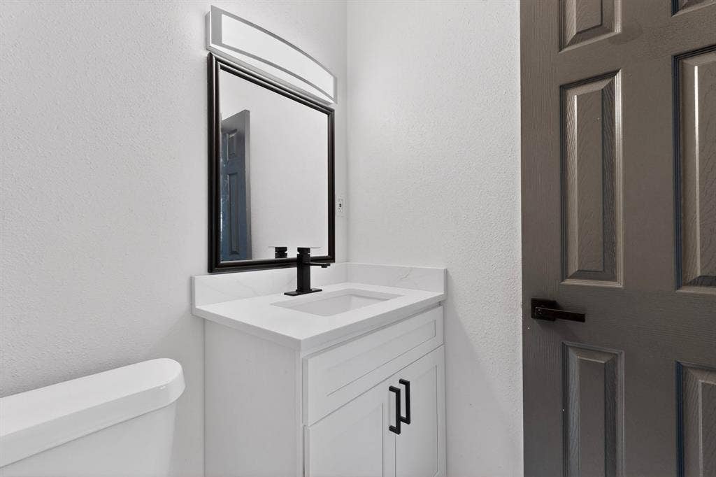 301 Stoneport Drive, Dallas, TX 75217 White vanity with a single basin, black faucet, and white countertop