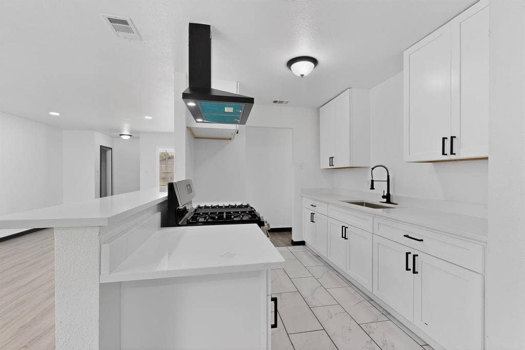 301 Stoneport Drive, Dallas, TX 75217 Kitchen featuring white flat-panel cabinetry, white countertops, a gas range with a black vent hood, a black pull-down faucet, and tiled flooring