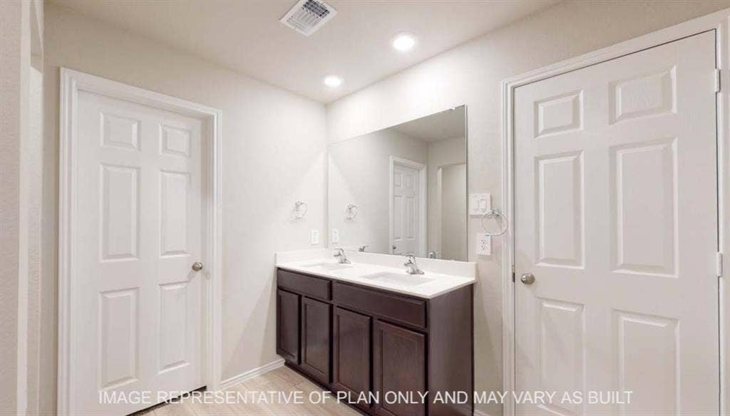 10412 Altair Drive, Waco, TX 76708 Dual vanity with dark wood-finish cabinetry, integrated sinks, and a large wall-mounted mirror
