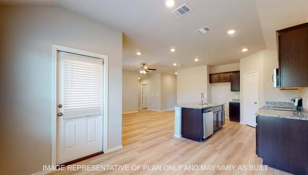 10412 Altair Drive, Waco, TX 76708 Kitchen featuring dark wood-finish cabinetry, granite-style countertops, stainless steel appliances, and a central island with an integrated sink
