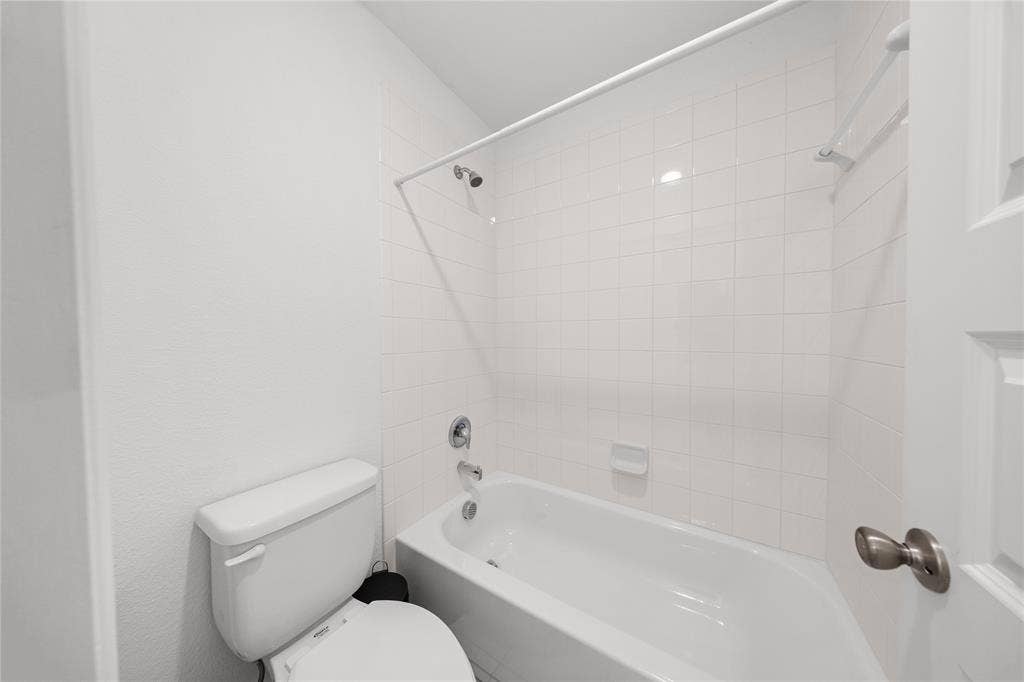 3955 Chesapeake Lane, Heartland, TX 75126 White tile shower surround, complete with a tub and shower combination, and a toilet
