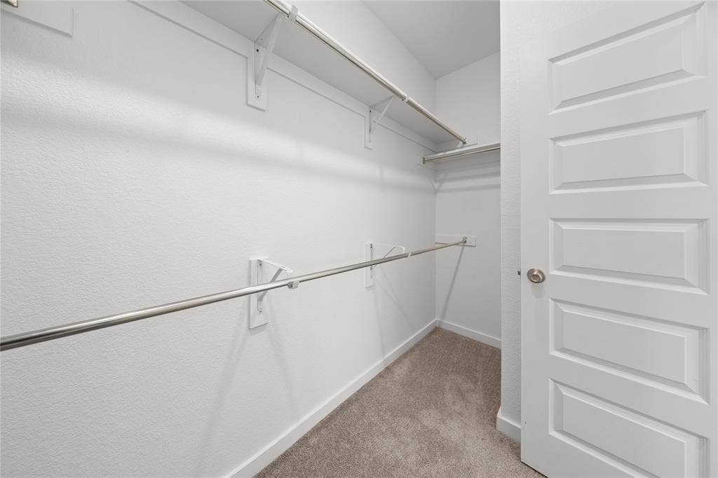 3955 Chesapeake Lane, Heartland, TX 75126 Walk-in closet featuring white painted walls, chrome hanging rods, white shelving, and a paneled white door