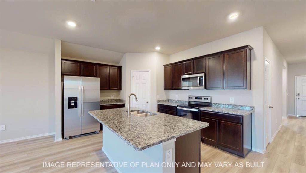 10405 Altair Drive, Waco, TX 76708 Kitchen featuring dark wood-finish cabinetry, stainless steel appliances, a central island with an undermount sink, and light wood-finish flooring