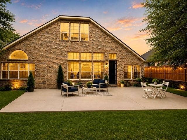 107 Appalachian Way, McKinney, TX 75071 Expansive brick exterior with a large concrete patio, manicured lawn, and multi-pane windows