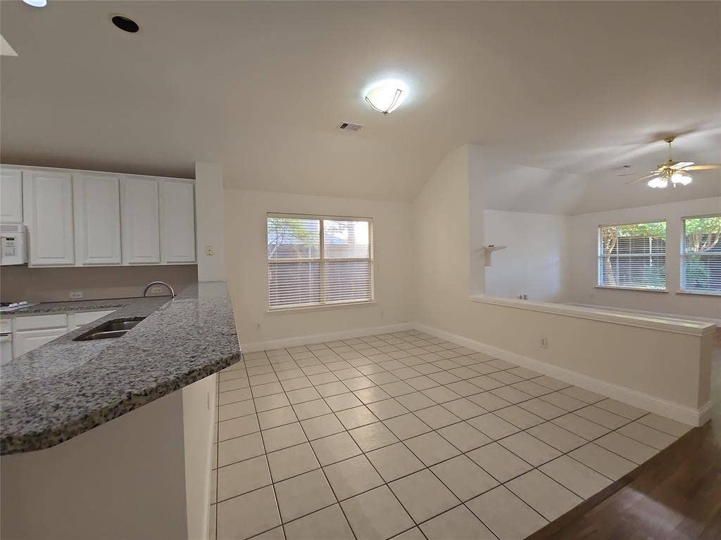 2424 Brycewood Lane, Plano, TX 75025 White cabinetry, granite countertops, tile flooring, and vaulted ceilings
