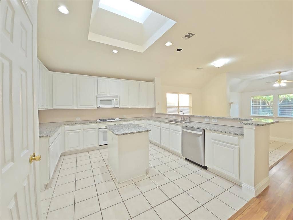 2424 Brycewood Lane, Plano, TX 75025 Kitchen featuring white cabinetry, light-toned countertops, a central island, and stainless steel appliances