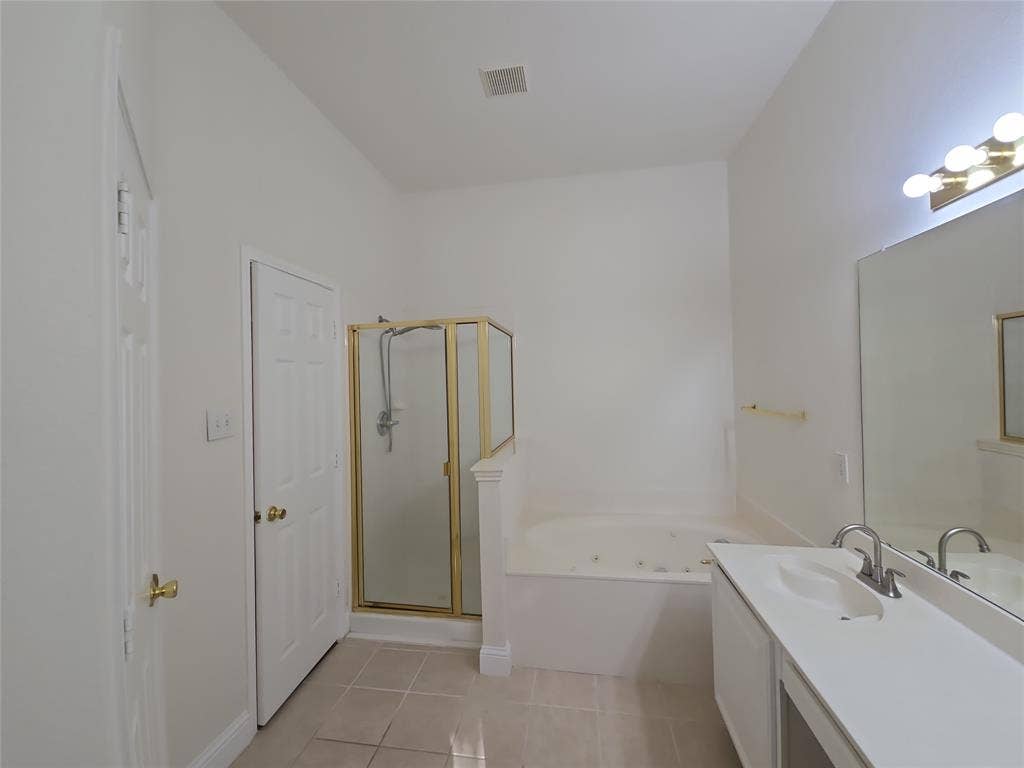 2424 Brycewood Lane, Plano, TX 75025 White paneled door, gold-framed shower enclosure, built-in bathtub, vanity with integrated sink, and large mirror with overhead lighting