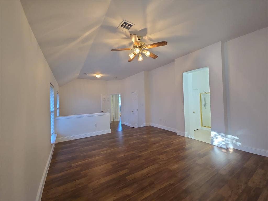 2424 Brycewood Lane, Plano, TX 75025 Wood-finish flooring, vaulted ceiling, ceiling fan, white interior paint, and a half-wall partition
