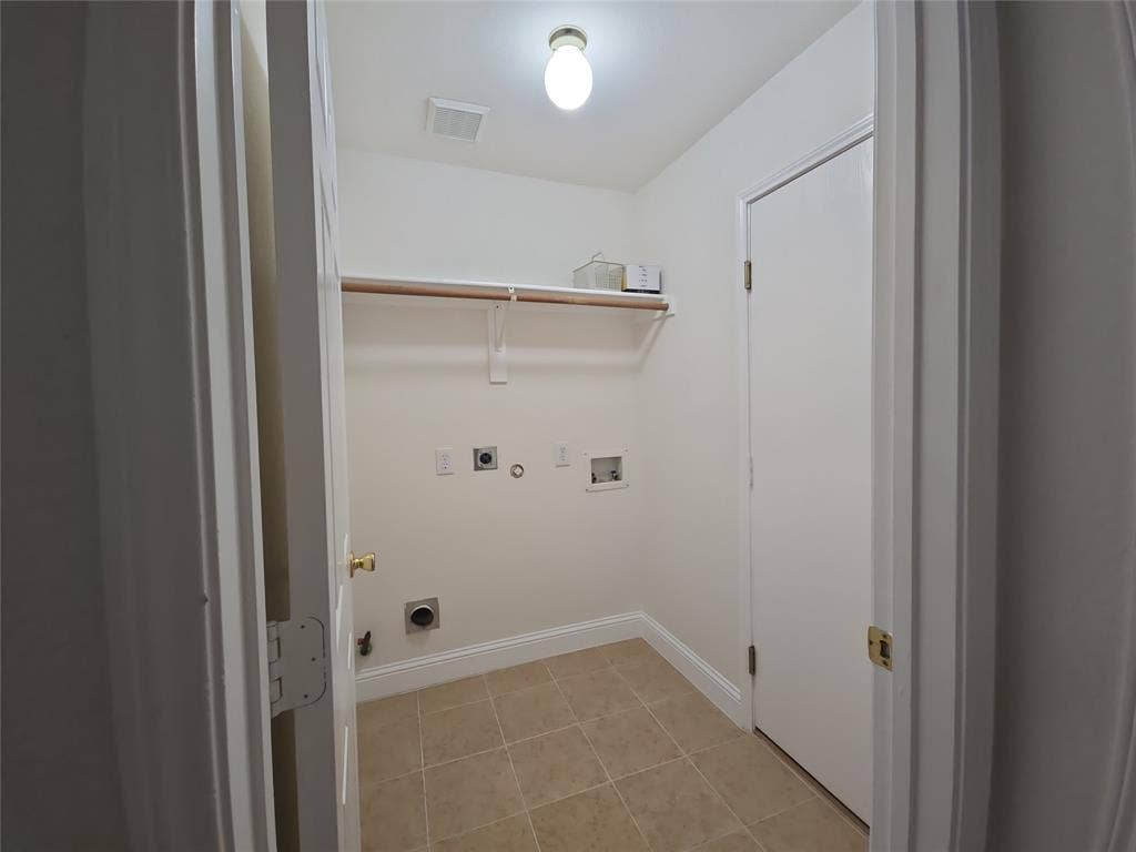 2424 Brycewood Lane, Plano, TX 75025 Utility room with neutral tile flooring, a wall-mounted shelf, and laundry hookups