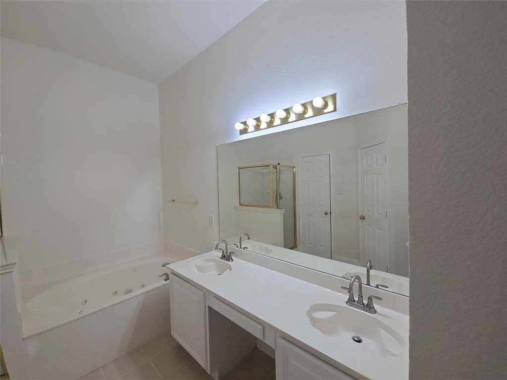 2424 Brycewood Lane, Plano, TX 75025 Dual vanity with undermount sinks, expansive mirror, vanity lighting, built-in cabinetry, and a jetted soaking tub