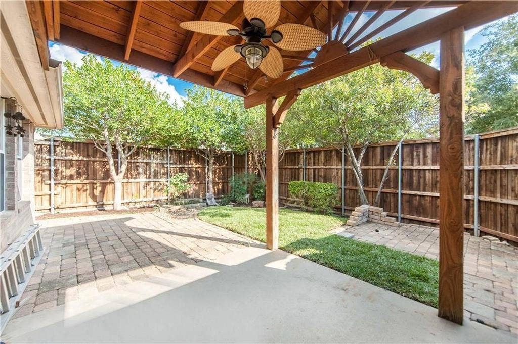 2424 Brycewood Lane, Plano, TX 75025 Covered patio with a ceiling fan, concrete and paver flooring, wood privacy fencing, and a manicured lawn