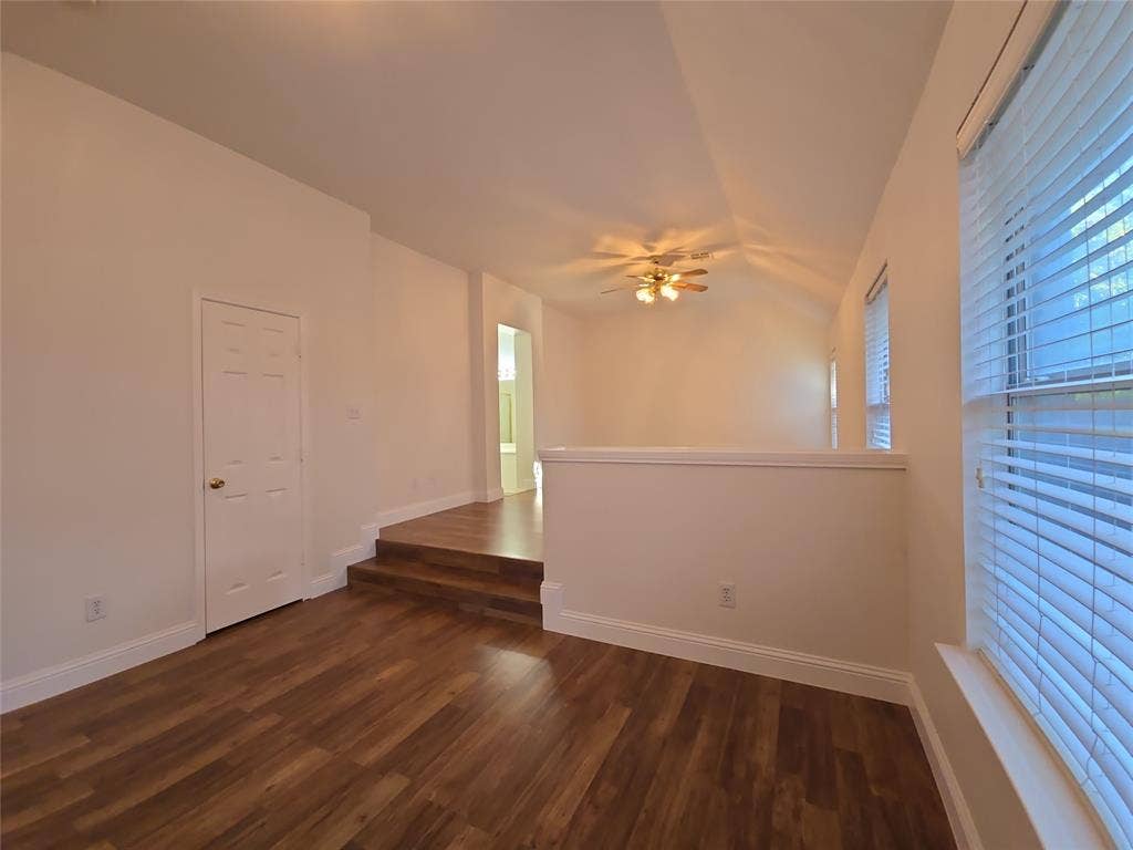 2424 Brycewood Lane, Plano, TX 75025 Vaulted ceiling with a ceiling fan, wood-finish flooring, multiple windows with blinds, and an interior door