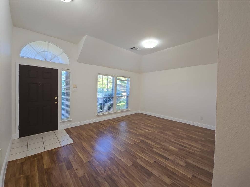 2424 Brycewood Lane, Plano, TX 75025 Wood-finish flooring, vaulted ceiling, and multiple windows with blinds