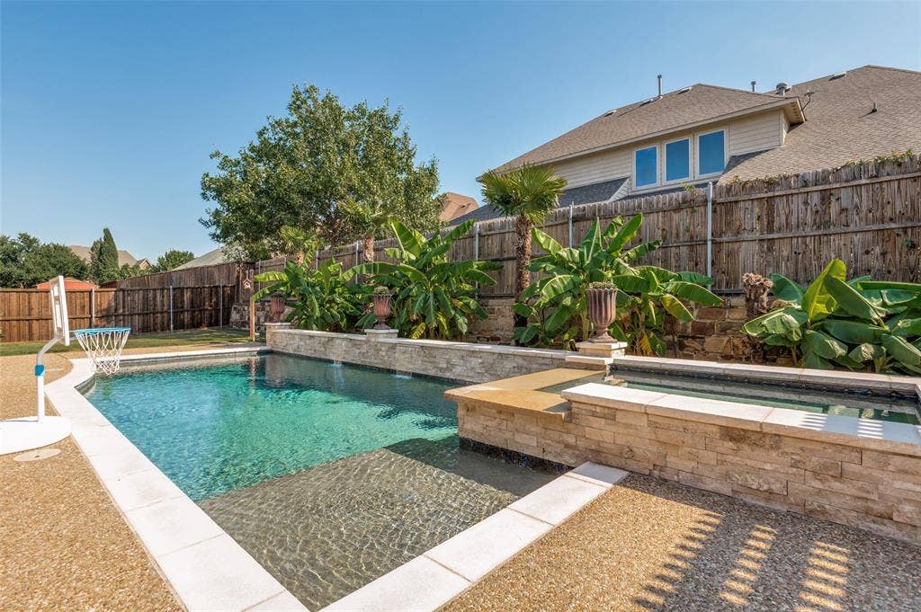 1504 Daisy Lane, Flower Mound, TX 75028 Swimming pool with a spa, stone-clad retaining walls, and surrounding landscaping