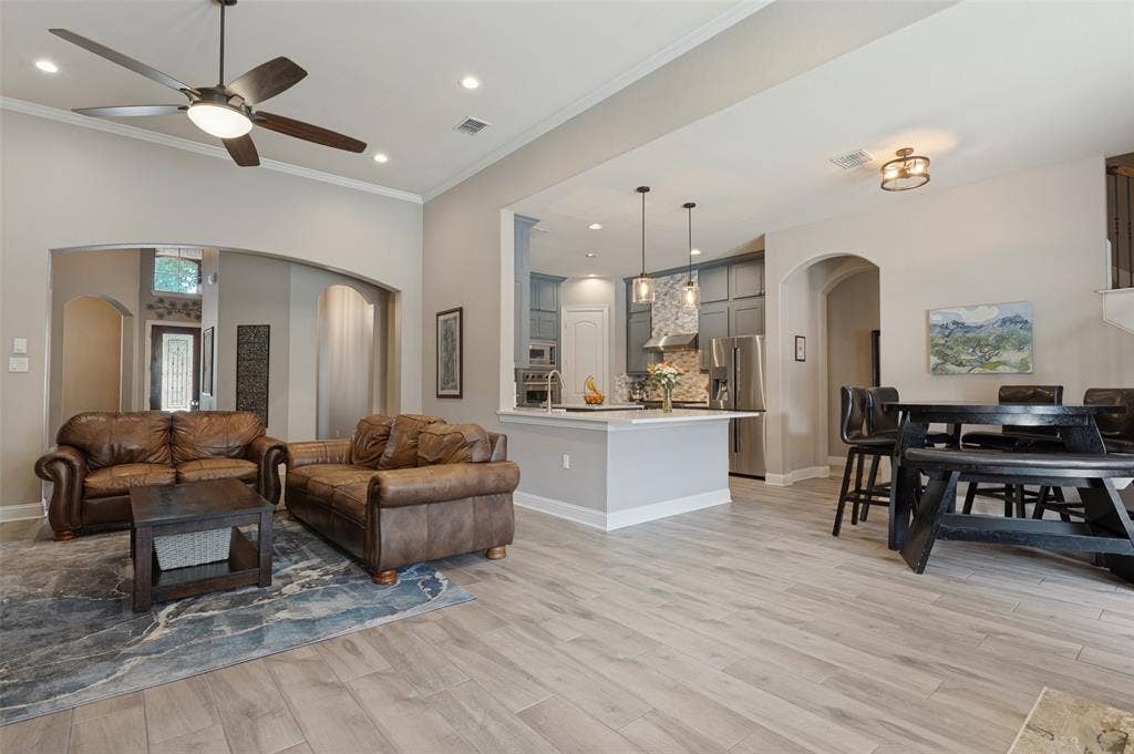 1504 Daisy Lane, Flower Mound, TX 75028 Wood-finish flooring throughout, recessed ceiling lighting, vaulted ceiling, arched doorways, and a kitchen island with pendant lighting