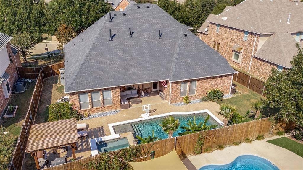 1504 Daisy Lane, Flower Mound, TX 75028 Brick exterior with a dark shingle roof, a concrete patio, and an in-ground swimming pool