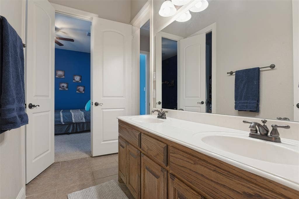 1504 Daisy Lane, Flower Mound, TX 75028 Double vanity with wood-finish cabinetry, dual undermount sinks, and bronze-finish faucets