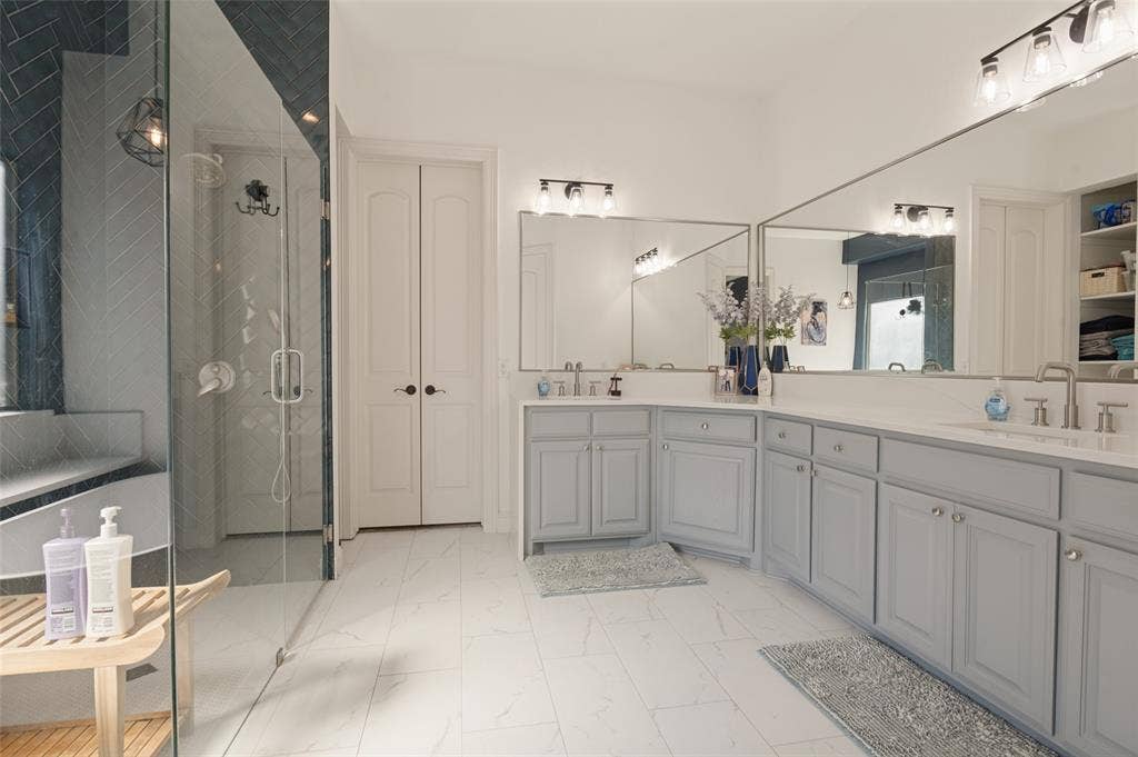 1504 Daisy Lane, Flower Mound, TX 75028 Spacious bathroom featuring an expansive dual vanity with light gray cabinetry and white countertops, a large frameless glass shower enclosure, and white tile flooring