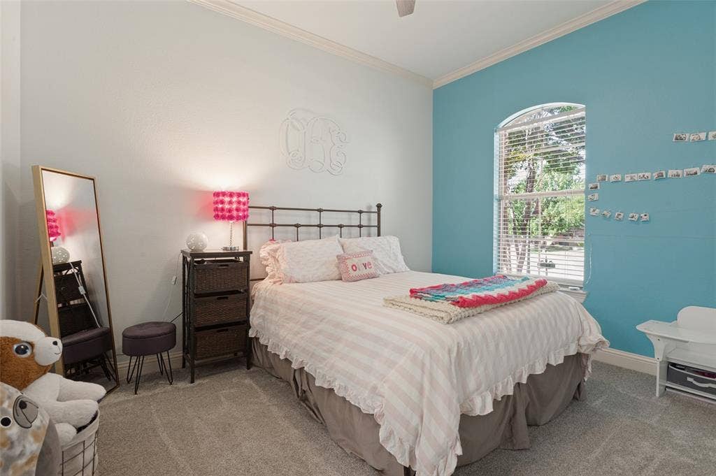 1504 Daisy Lane, Flower Mound, TX 75028 Arch-top window with blinds, wrought iron bed frame, crown molding, and carpeted flooring