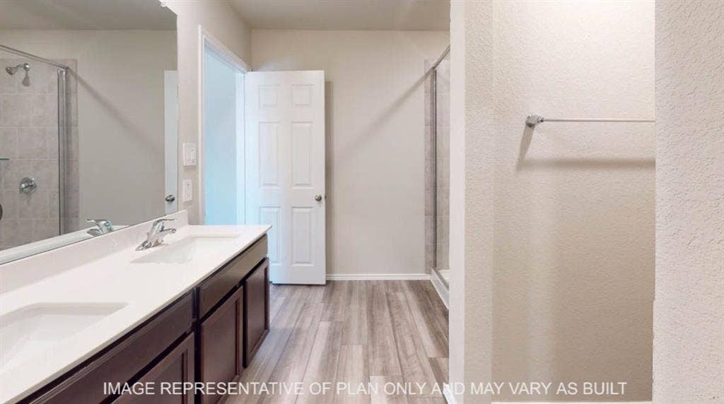 10112 Altair Drive, Waco, TX 76708 Dual vanity with integrated sinks, wood-finish flooring, glass-enclosed shower, and a six-panel interior door
