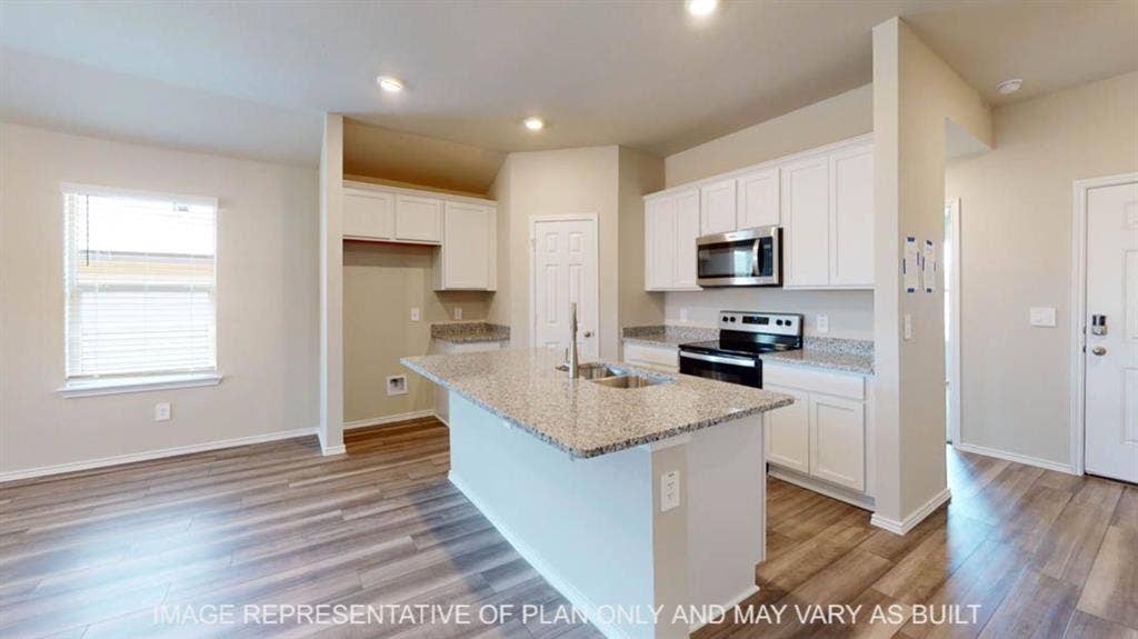 10112 Altair Drive, Waco, TX 76708 Kitchen featuring an island with a stainless steel sink, wood-finish flooring, white cabinetry, granite countertops, and stainless steel appliances