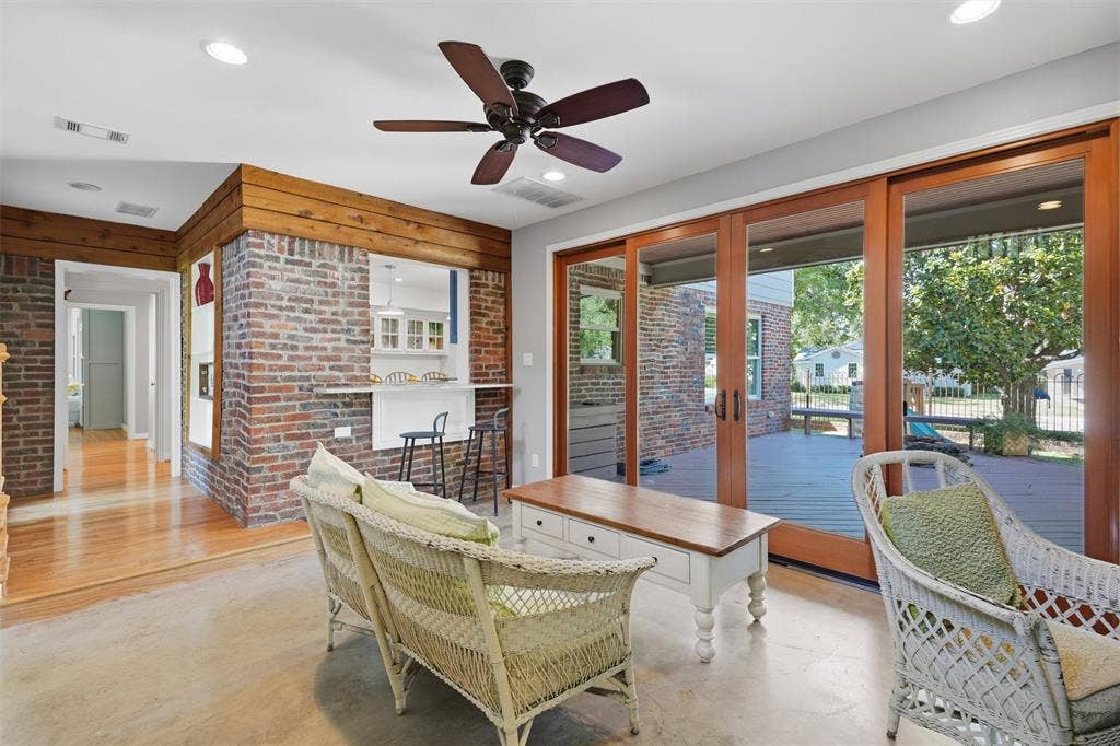 3712 Brighton Road, Fort Worth, TX 76109 Alternate sunroom angle showing the pass-through breakfast bar connected to the kitchen. Highlights exposed brick walls, warm wood trim, and direct sliding glass door access to the back deck.