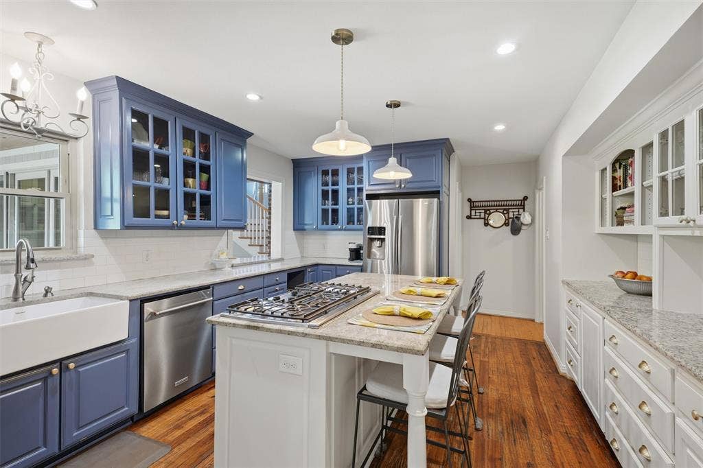3712 Brighton Road, Fort Worth, TX 76109 Alternate kitchen perspective highlighting the island with built-in gas cooktop and breakfast bar seating. Features an apron-front sink, stainless steel appliances, and extensive cabinetry