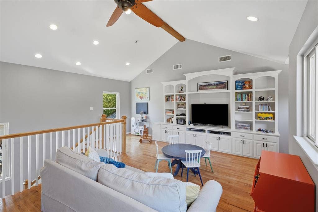 3712 Brighton Road, Fort Worth, TX 76109 Spacious upstairs family room featuring vaulted ceilings with custom built-in media shelving, hardwood flooring, and a safety railing.